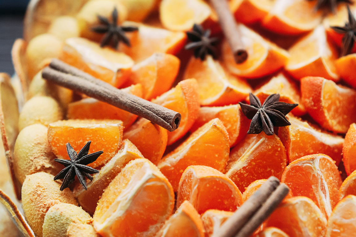 Delicious vegan citrus dessert decorated with fresh oranges and dry spices, cinnamon sticks and star anise. Selective focus. Colorful, healthy and juicy. Top view, for cafe menu or confectionery catalog