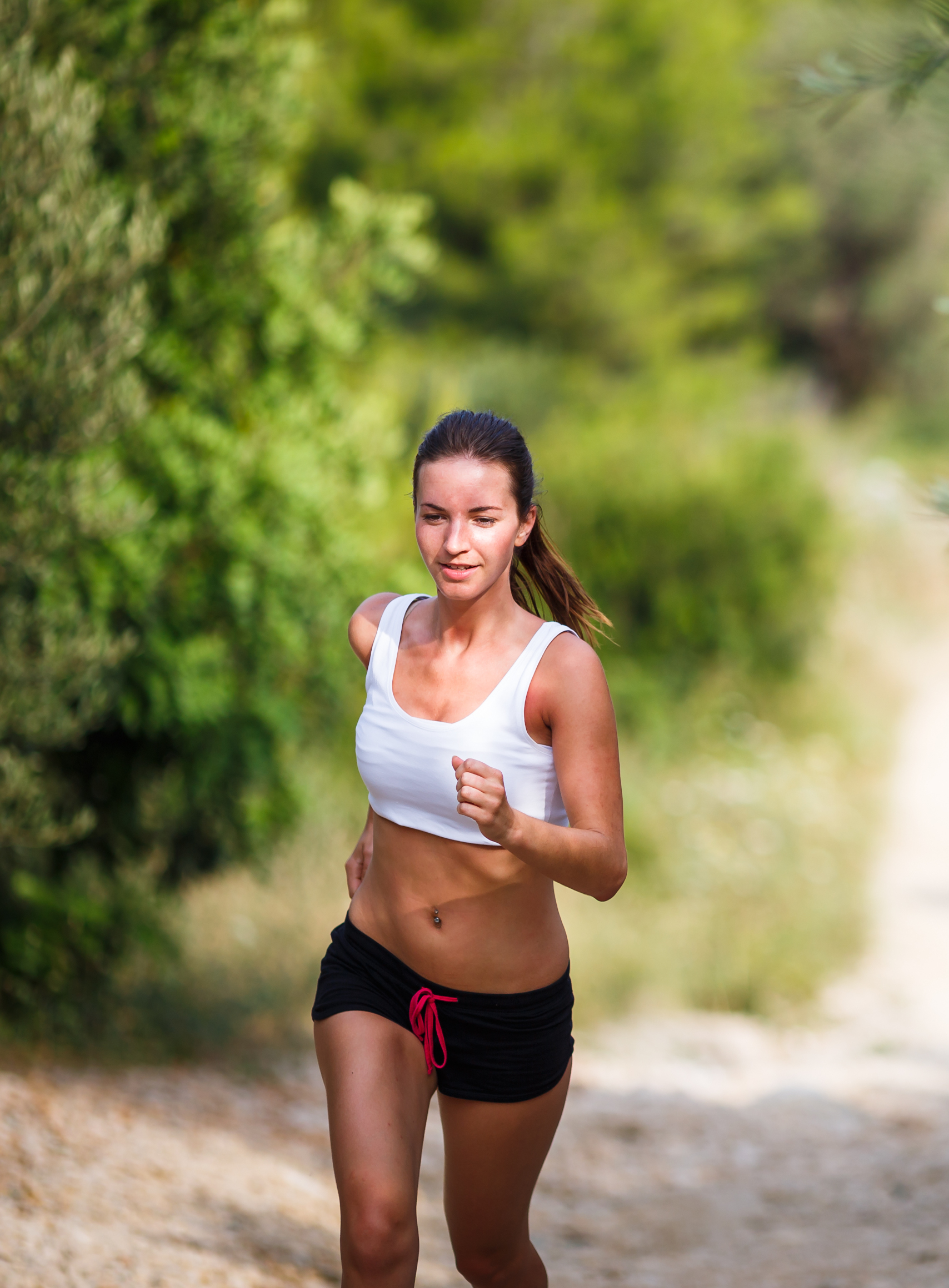 Beautiful young female runner on a forest path, on a lovely summer day